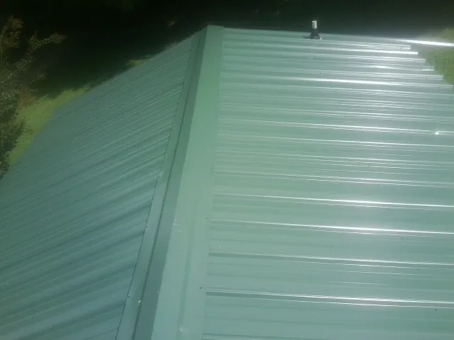 New green metal panels meeting at the ridge of a roof — Flat Roof Repair work by our crew in Los Alamos