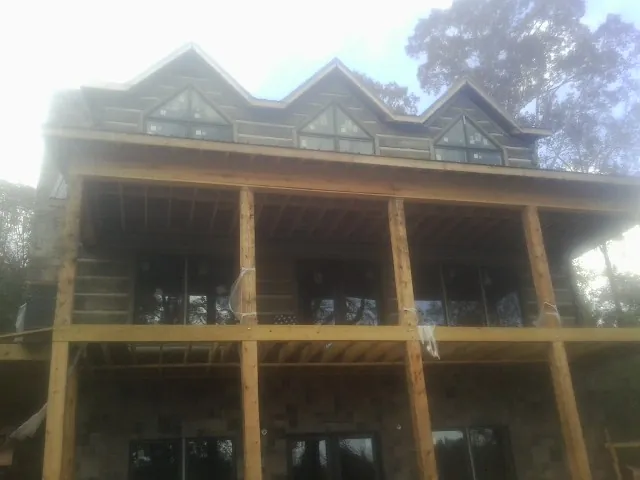 Dormers and porch framing on a large log home under construction — Roof Coating work by our crew in Los Alamos