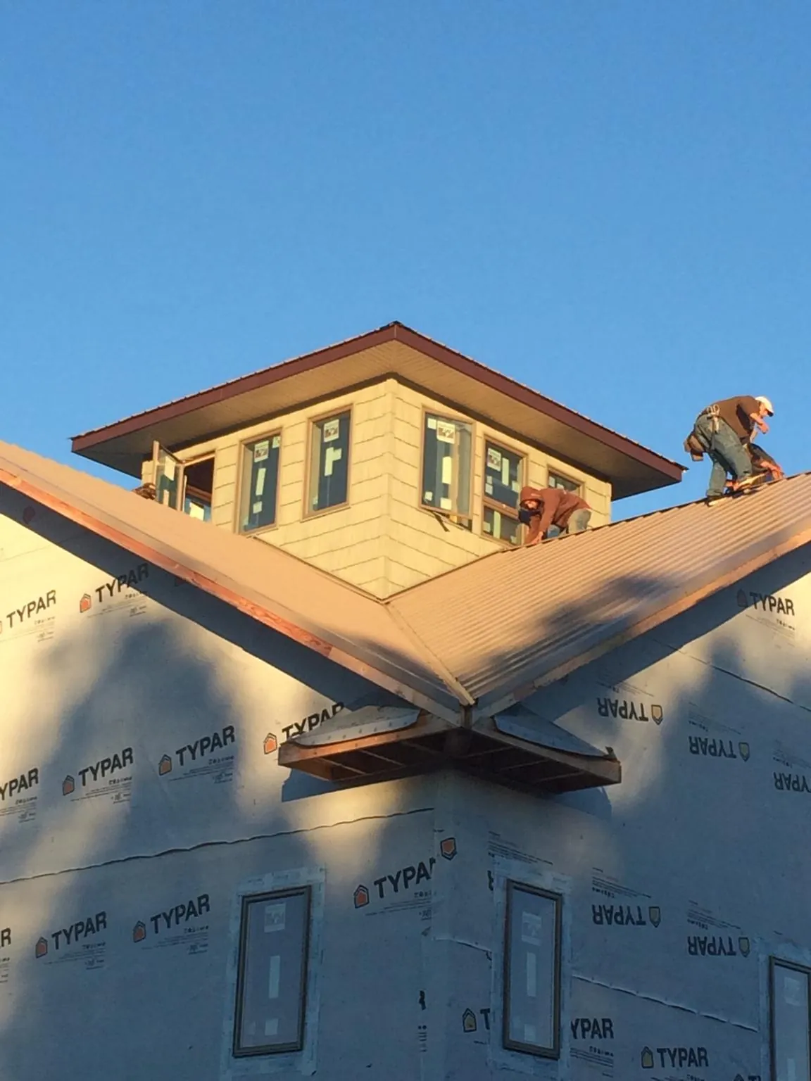 Roofers working around a rooftop cupola on a new metal roof at sunset — Roof Waterproofing in Los Alamos by Roofing Brothers